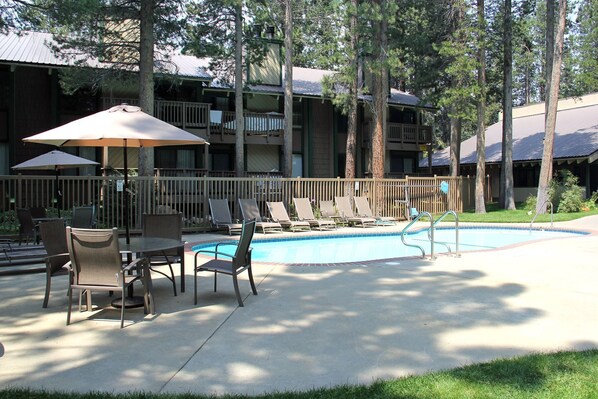 Relax by the resort's pool surrounded by lounge chairs and a shaded table.