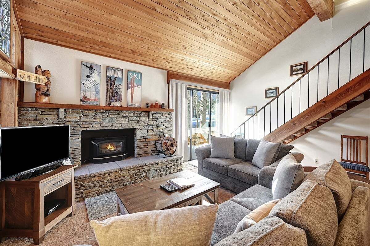 Ein gemütliches Wohnzimmer mit Kamin aus Stein, einem Fernseher und einer bequemen Sitzecke.