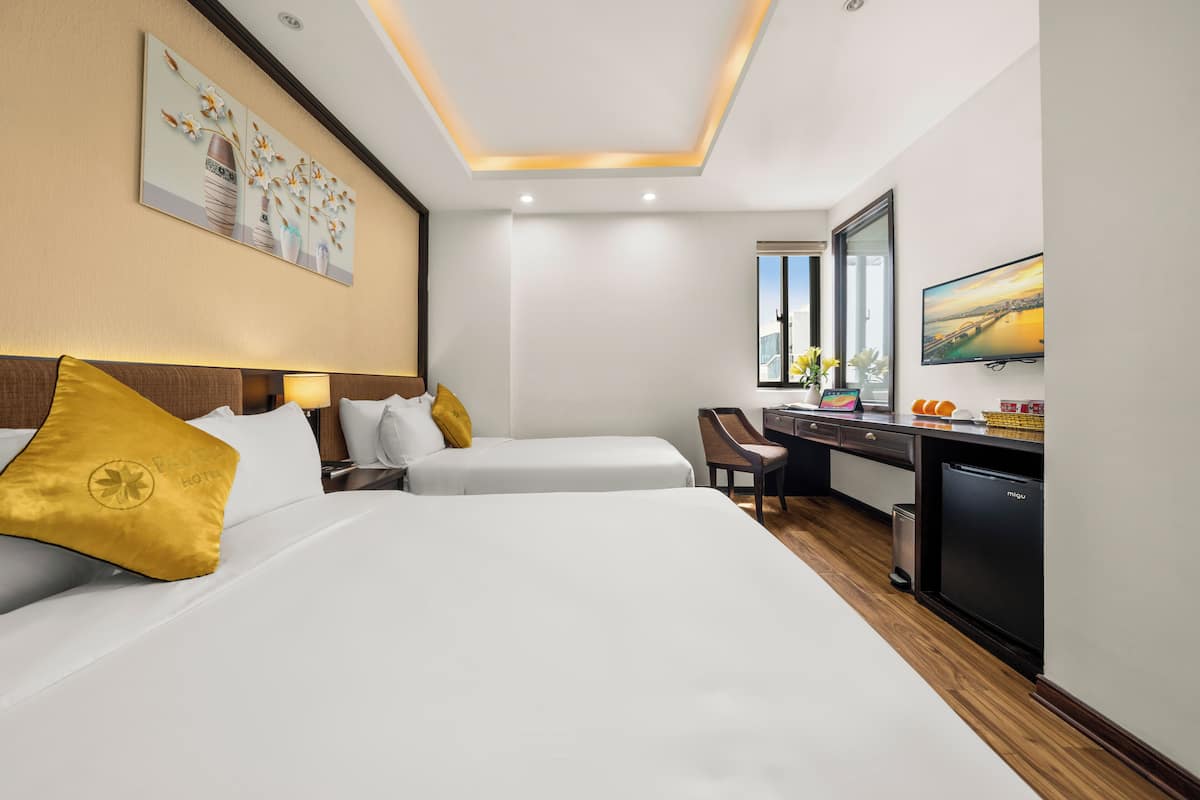 A hotel room with two beds, a desk, a chair, a television, and a window with a cityscape view.