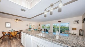 A spacious kitchen with a granite countertop, white cabinets, and a large window offering a view of the outdoors. - Come and enjoy our large intercoastal beach suite with pool (Indian Shores)