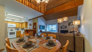 Un comedor con una mesa redonda de madera dispuesta para cuatro personas, un sofá y una lámpara de pie.