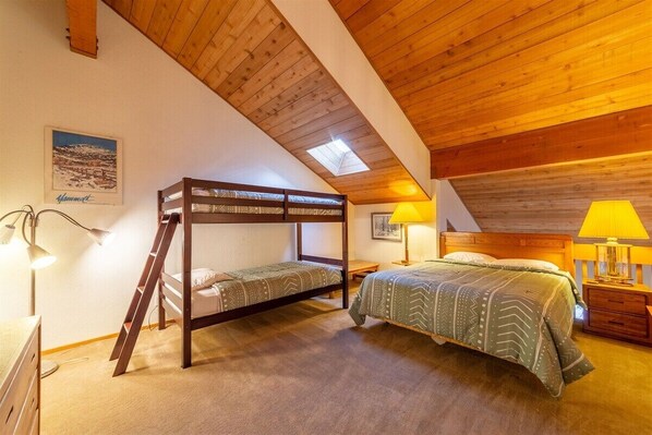 Ein gemütliches Schlafzimmer mit einem Etagenbett, einem Schreibtisch und einer Lampe.