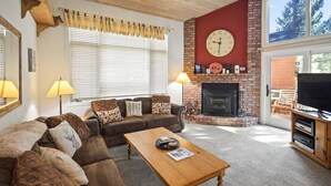 A cozy living room with a fireplace, a sofa, a coffee table, and a television. - Woodlands 28: Pet Friendly, On Sierra Star Golf Co (Mammoth Lakes)