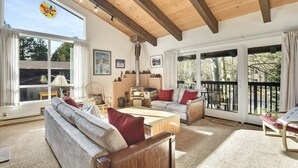 A cozy living room with a fireplace, large windows, and a balcony. - Chateau Blanc 30: One car garage, near town (Mammoth Lakes)