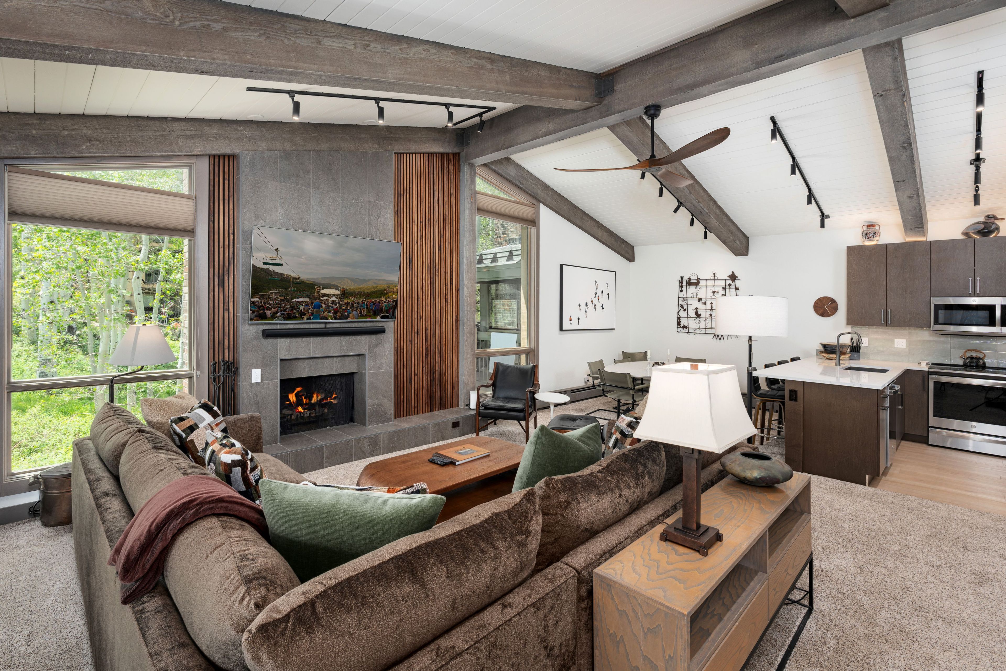A modern living room with a fireplace, a dining area, and a kitchen.