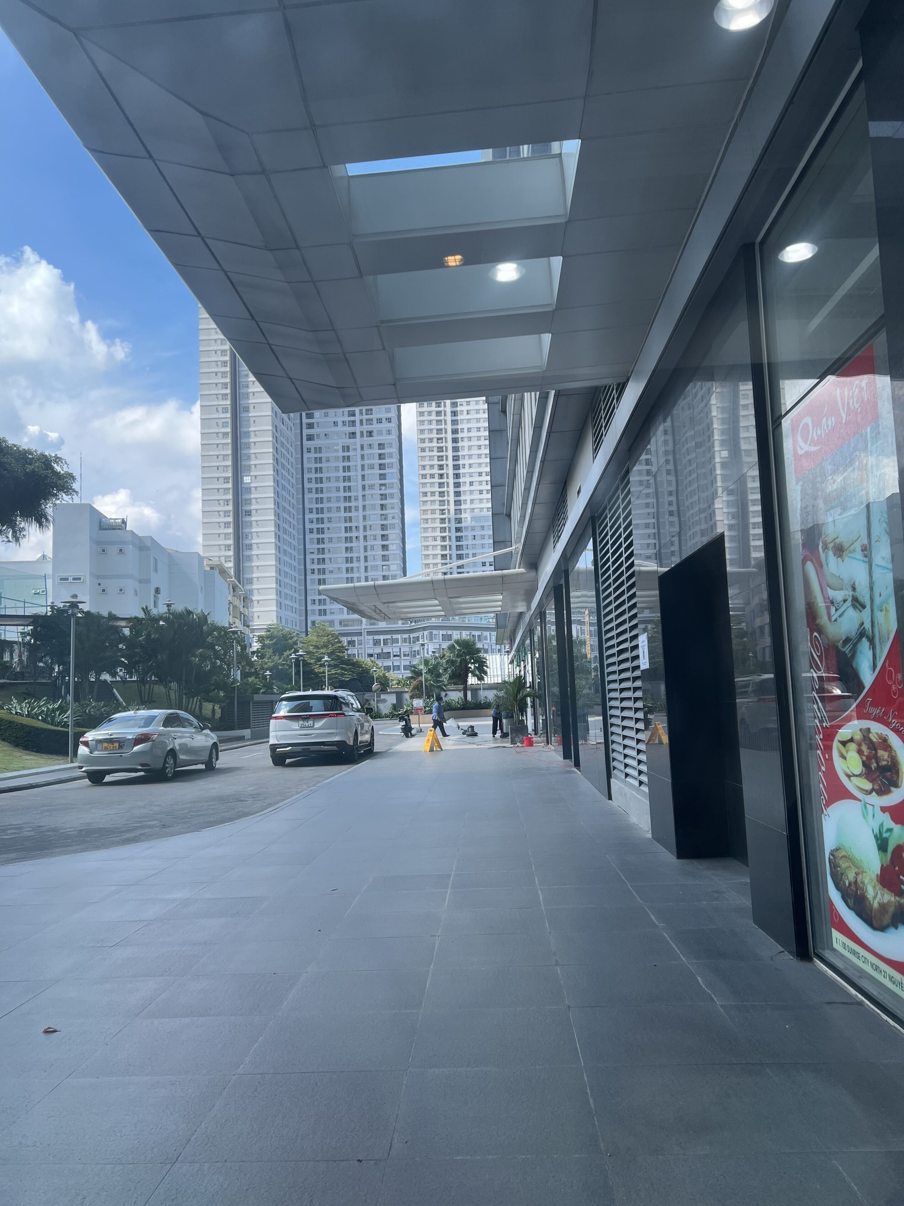 A modern building with a glass facade, a paved entrance, and a clear sky.