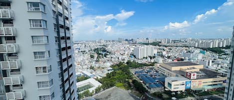 A high-rise building with multiple balconies and a view of a cityscape with various buildings and a river.