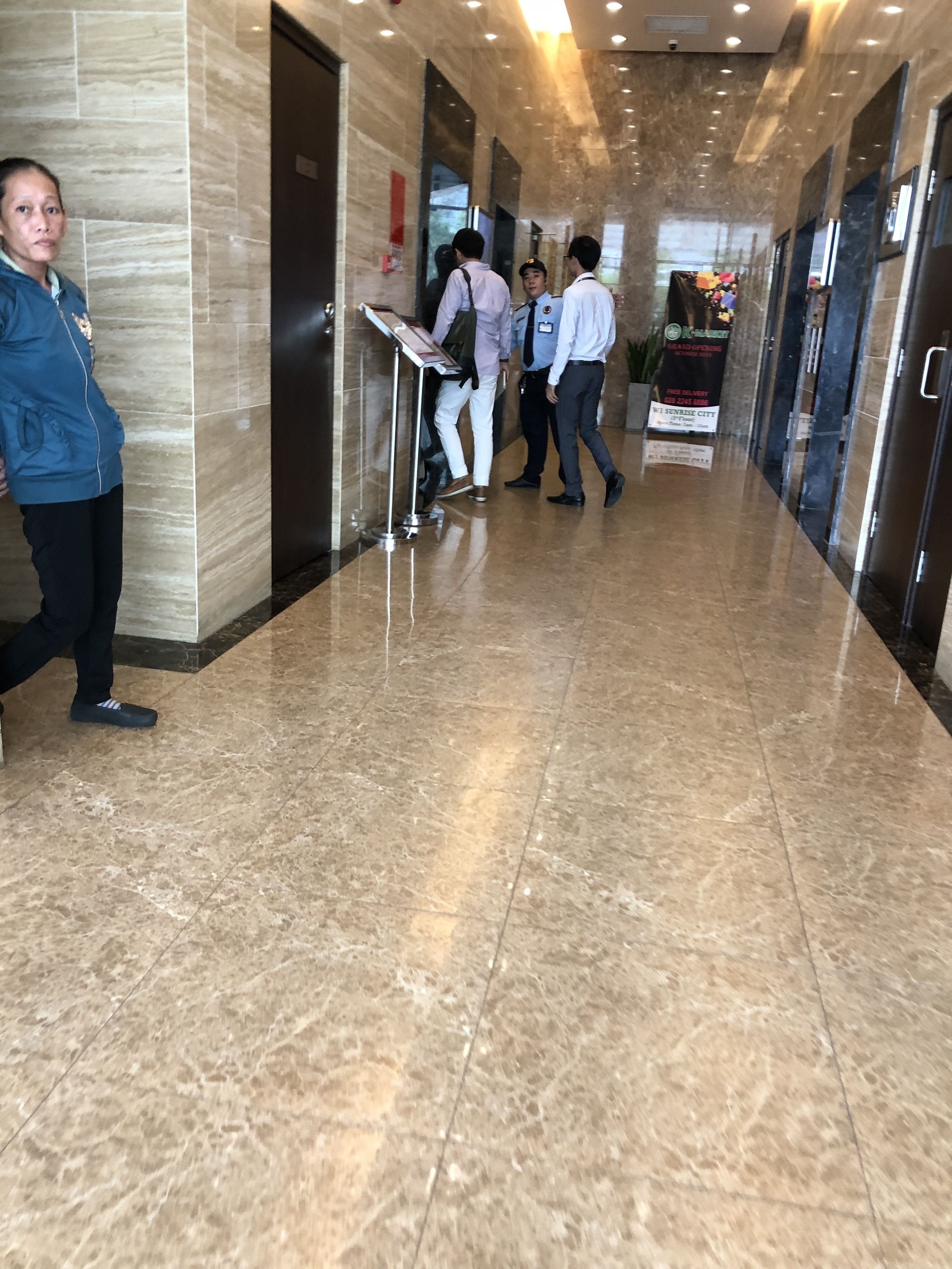 A hotel lobby with marble flooring, a reception desk, and a sign for a restaurant.