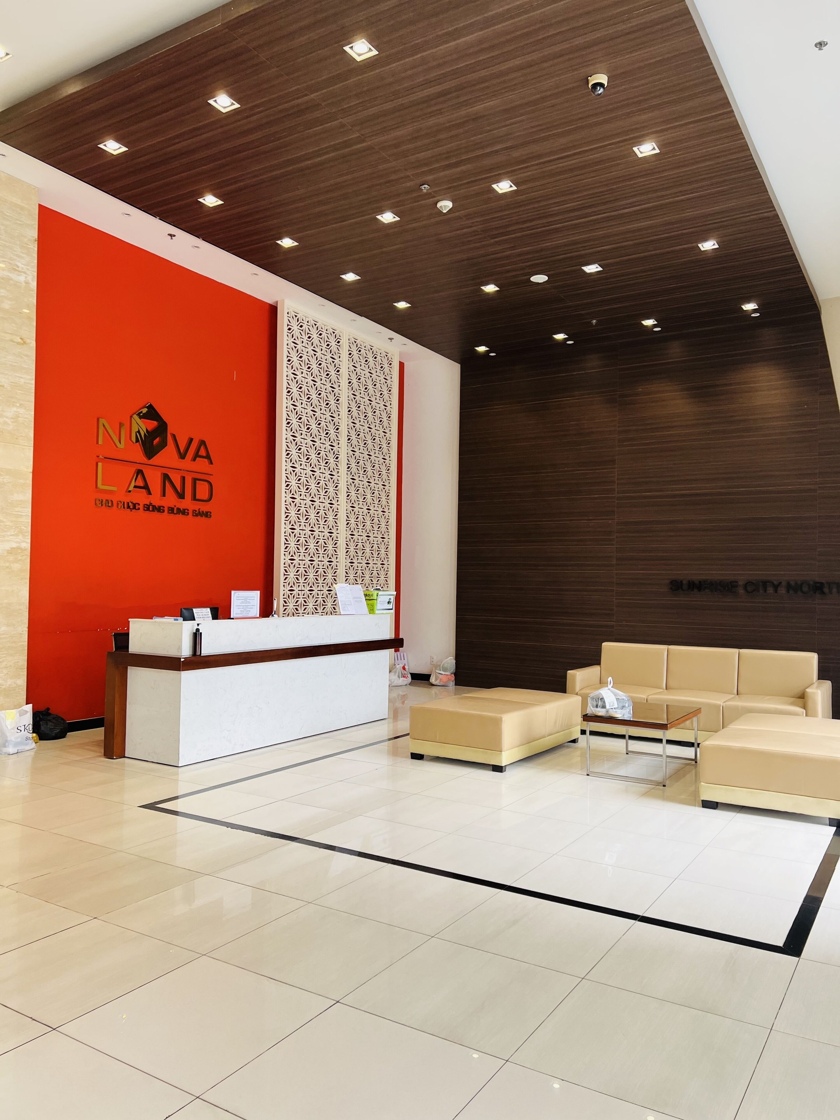 Un moderno vestíbulo de hotel con un mostrador de recepción, un muro con diseño y una zona de estar.