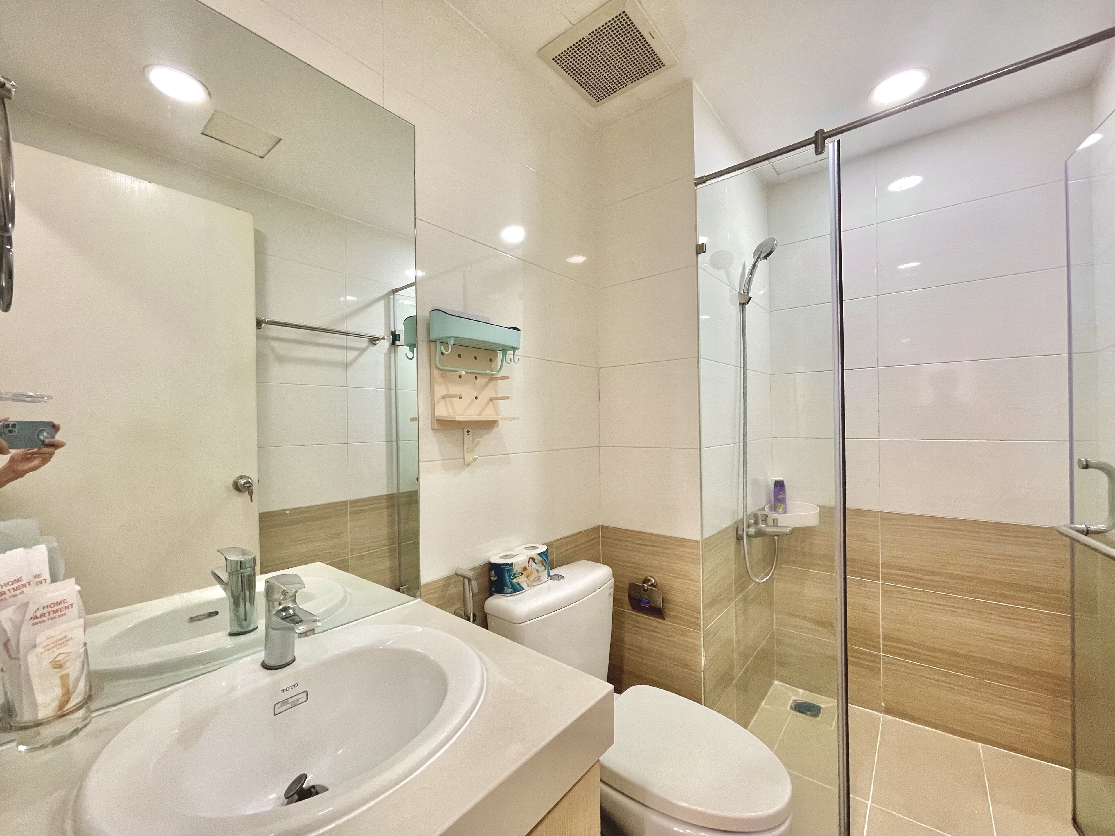 A modern bathroom with a glass shower enclosure, a white sink, and a toilet.