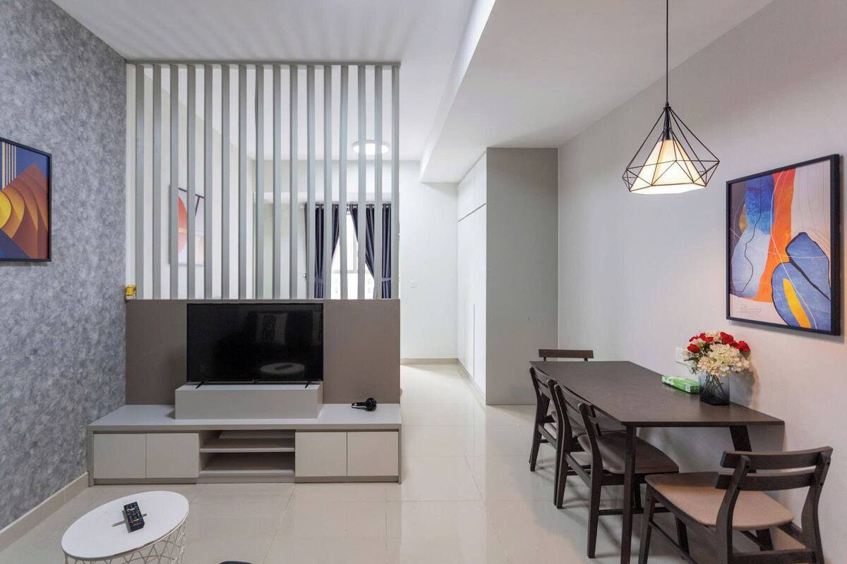Ein modernes Wohnzimmer mit Flachbildfernseher, einem Essbereich mit Tisch und Stühlen sowie einer dekorativen Vase mit Blumen.