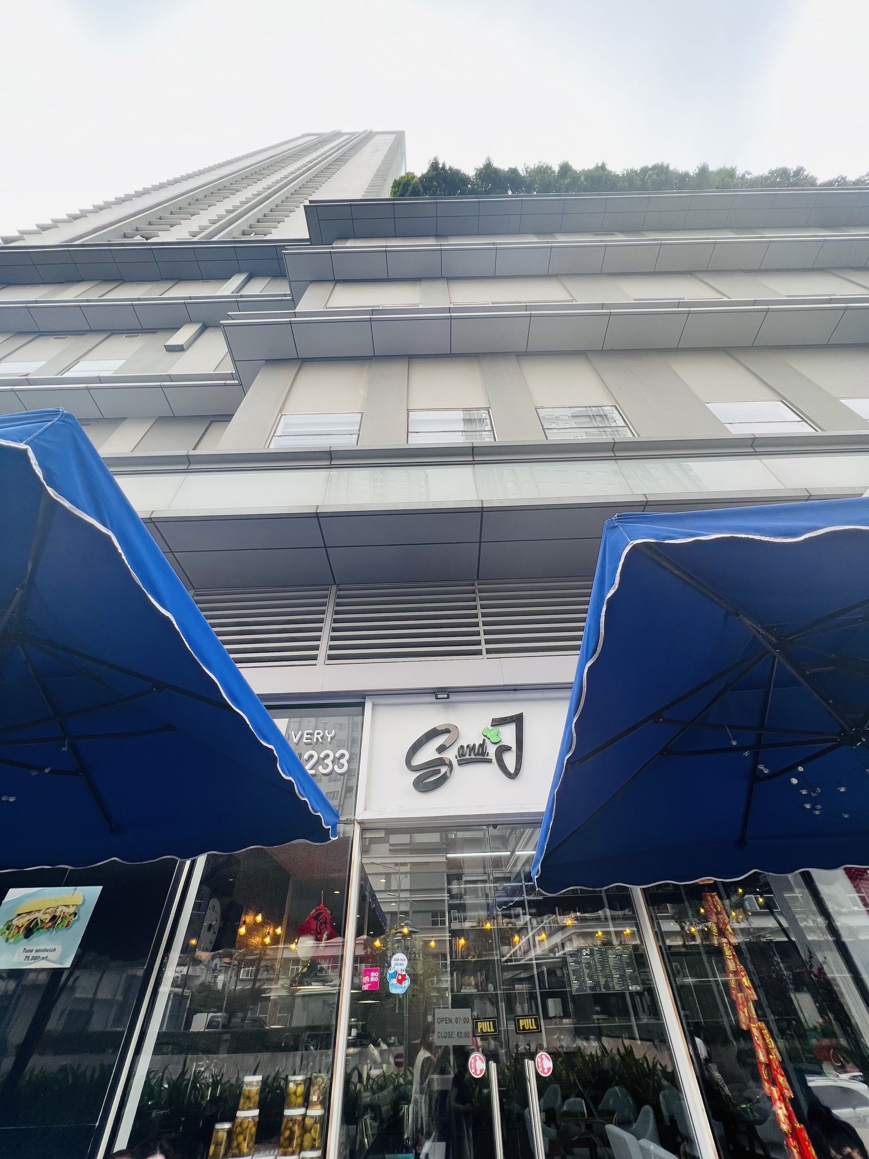 A building with a sign reading "Sand" and a blue awning.