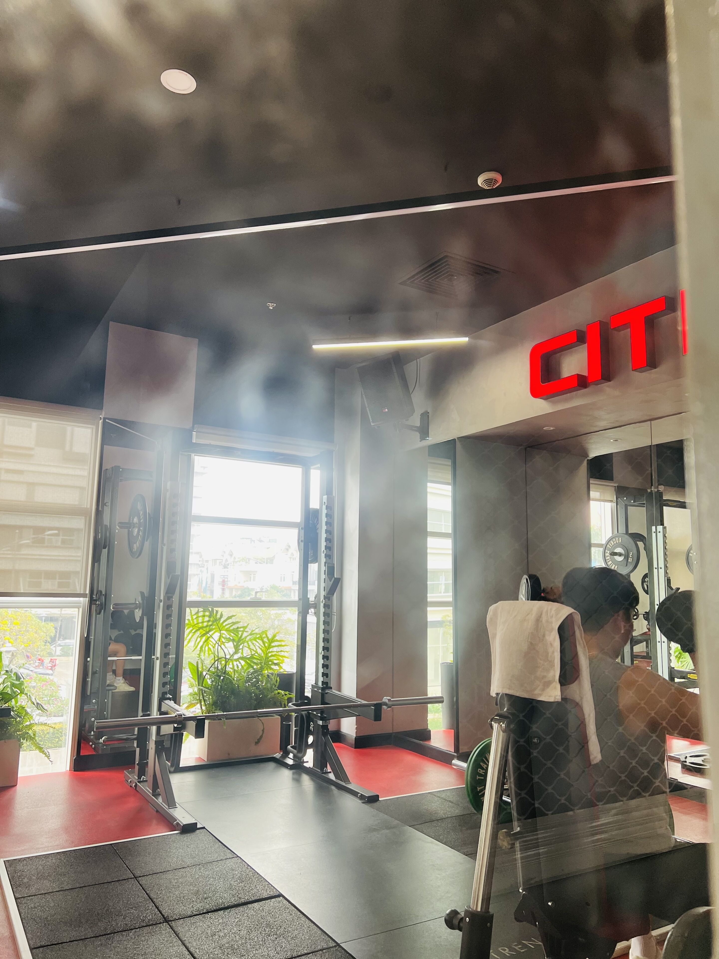 A gym with a red floor, weightlifting equipment, and a large window.