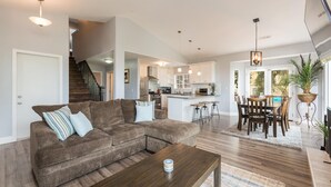 A modern living room with a brown sectional sofa, a wooden coffee table, and a dining area with a wooden table and chairs. - Fabulous 4 Bed/3 Bath Rental on Lodge Hill! Updated, Charming & Pet-Friendly! (Cambria)