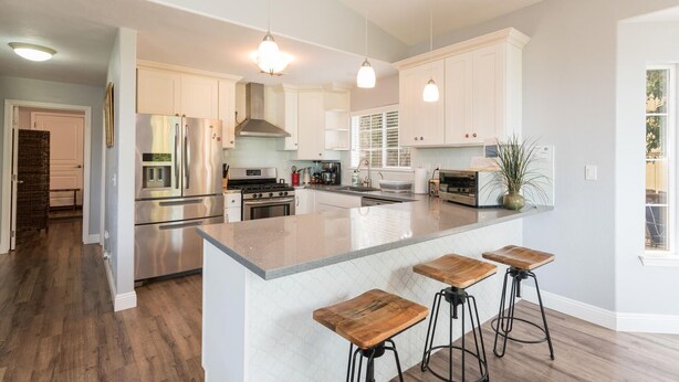 A modern kitchen with white cabinets, stainless steel appliances, and a central island with bar stools. - Fabulous 4 Bed/3 Bath Rental on Lodge Hill! Updated, Charming & Pet-Friendly! (Cambria)