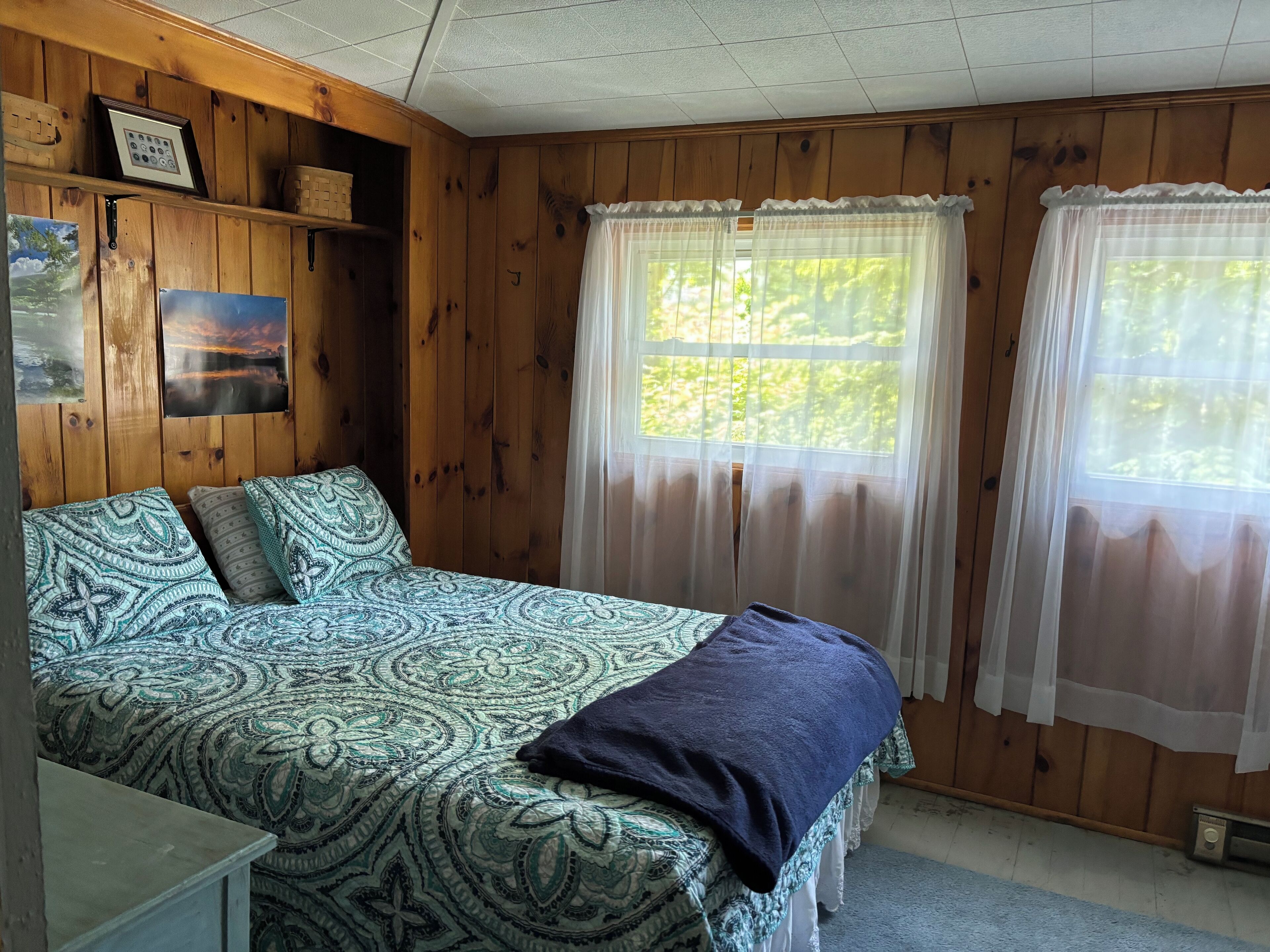 Un dormitorio acogedor con cama, cómoda y ventana con cortinas translúcidas.