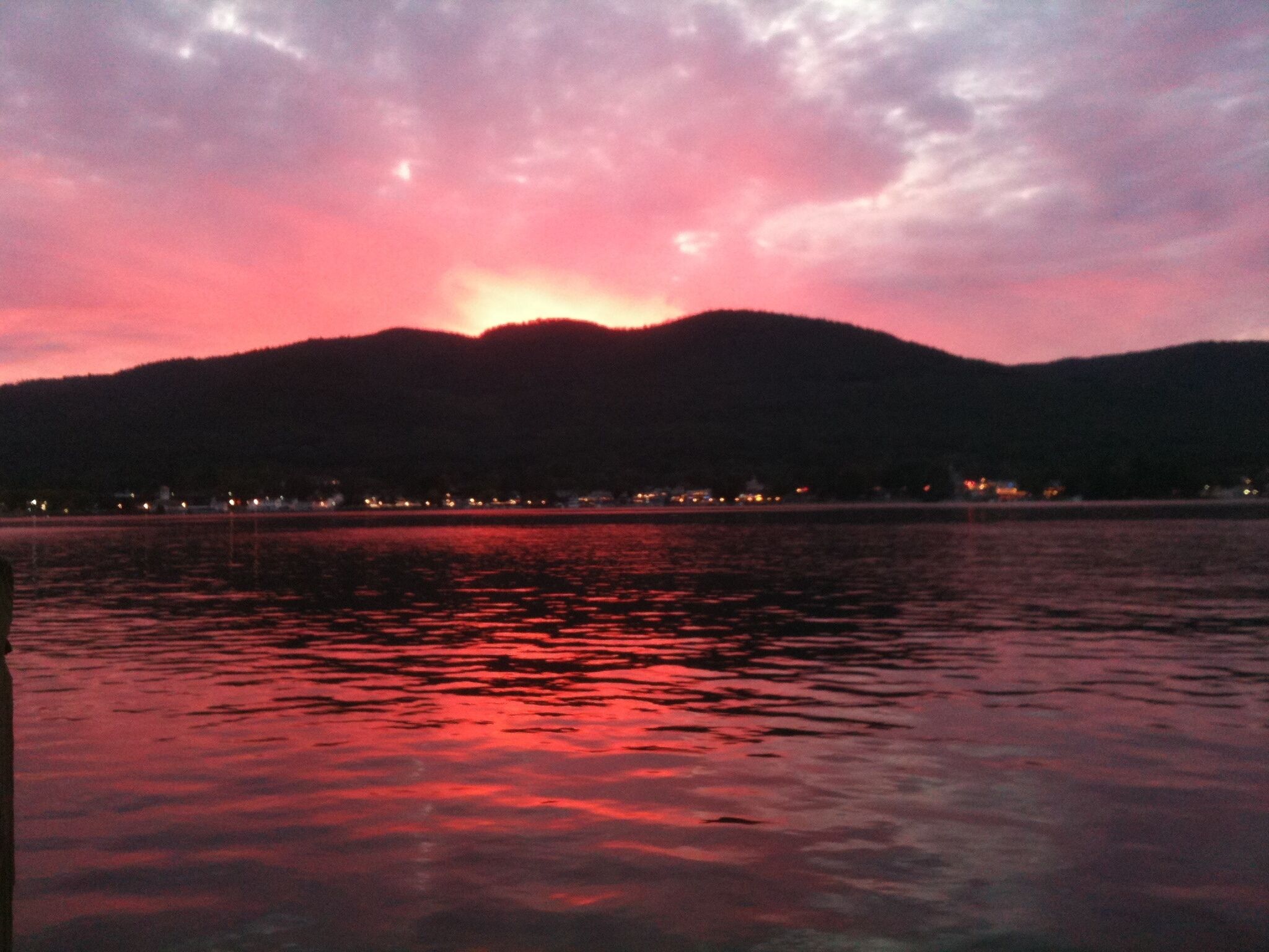 A sunset over a body of water with a mountain in the background.