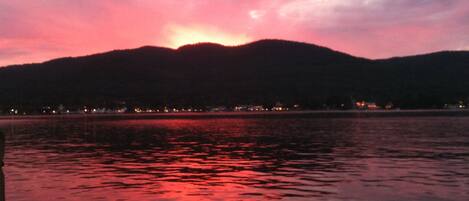 A sunset over a body of water with a mountain in the background.