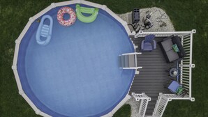 An above-ground swimming pool with a deck area featuring a seating arrangement and a small table. - Spacious/Comfy/Private Home near Buffalo/Bills/Airport/Niagara Falls (Depew)