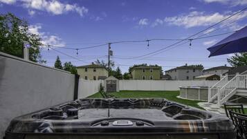 En trädgård med en bubbelpool, ett vitt staket och hus i bakgrunden.