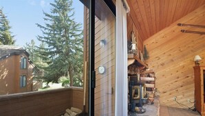 Una cabaña de madera con chimenea de piedra, un reloj y vista a un bosque.
