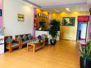 A reception area with a sofa set, a coffee table, and a potted plant. - Hotel Hoang Gia (Hanoi)