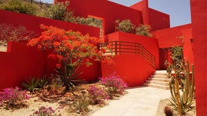 A red building with a staircase and a small garden with cacti and flowering plants. - The Red House - Quiet, romantic weekend (Los Barriles)