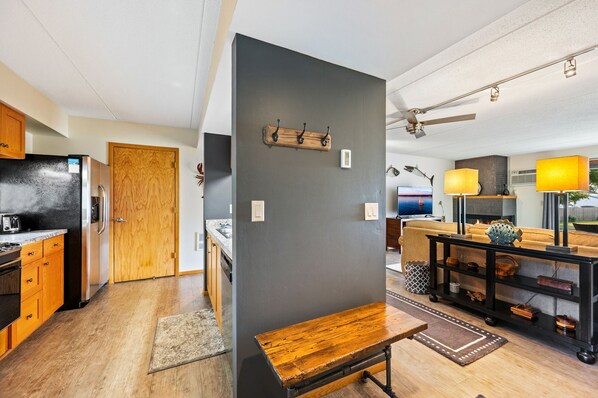 A modern kitchen with wooden cabinets, a black refrigerator, and a wooden bench.