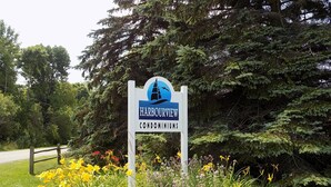 Schild für das Harbourview Condominiums mit Leuchtturm-Logo, umgeben von Pflanzen und Blumen.