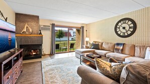 Ein Wohnzimmer mit Kamin, einer großen Uhr, einer Couch und einem Fernseher.
