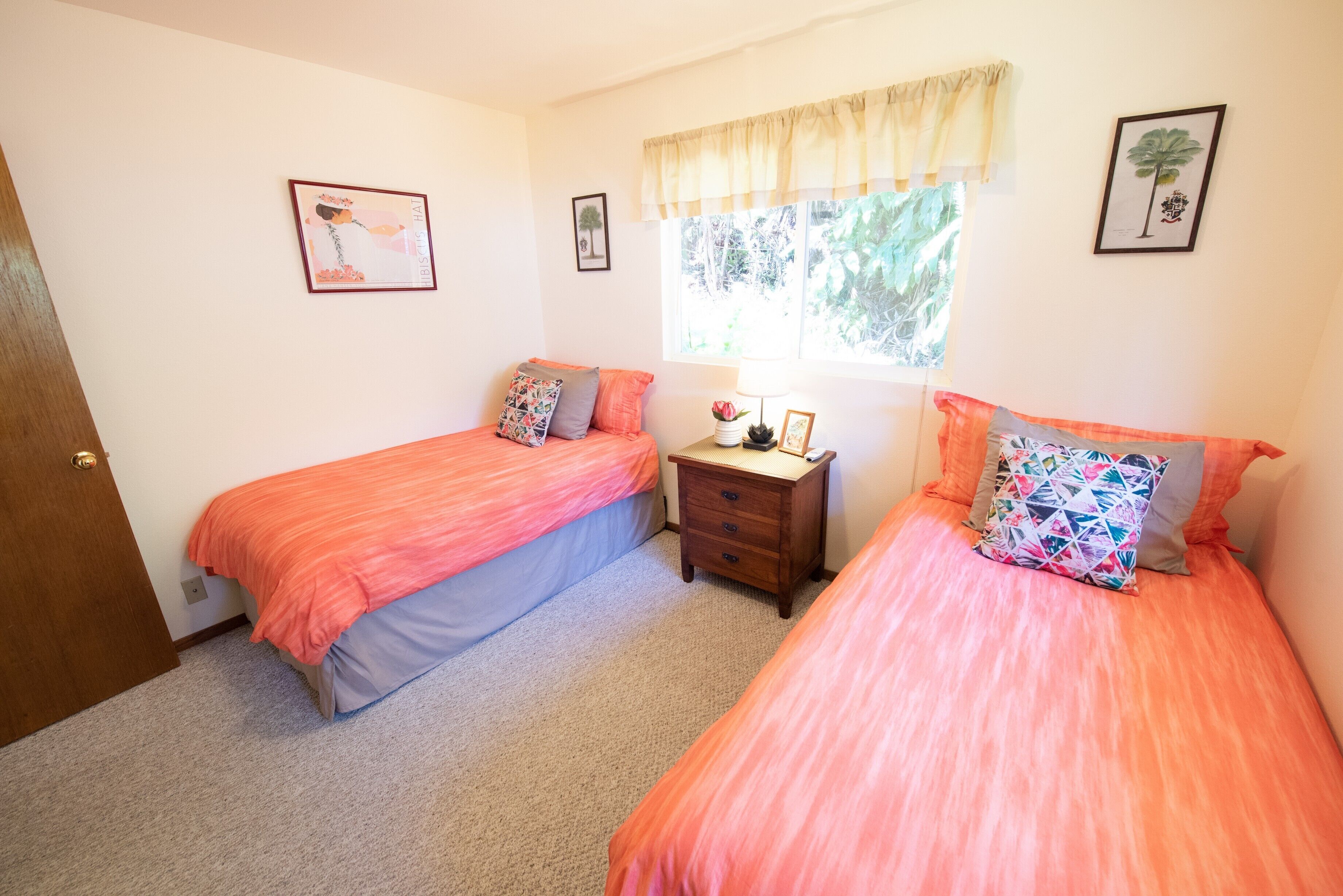Un dormitorio con dos camas, una mesita de noche, una ventana con cortinas y decoración en la pared.