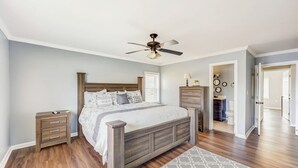 A bedroom with a wooden bed, nightstands, a ceiling fan, and a patterned rug.