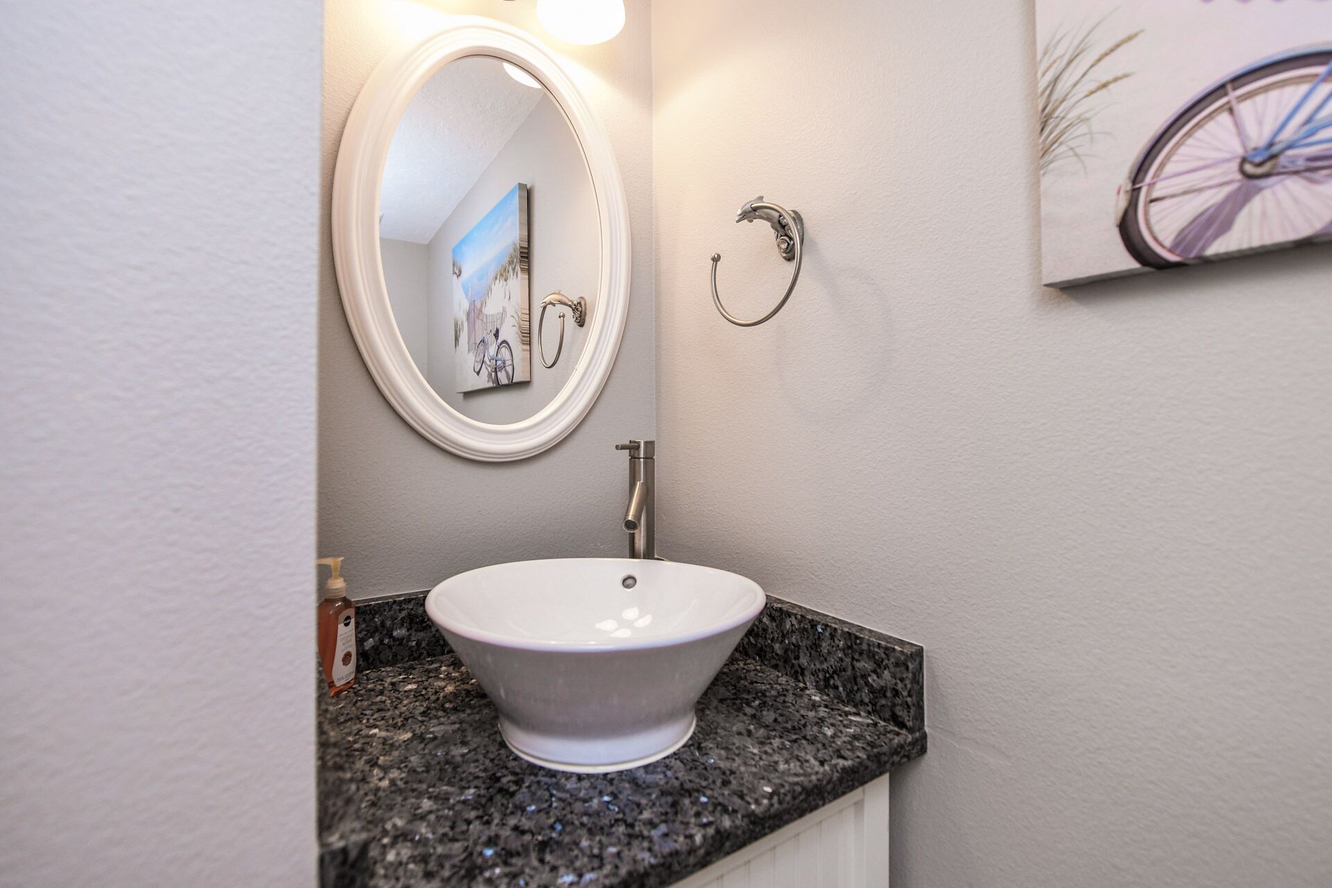 A bathroom with a white sink, a round mirror, and a towel ring.