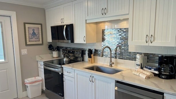 A modern kitchen with white cabinetry, stainless steel appliances, and a tiled backsplash. - Condo with Private Beach Access, Great Shared Amenities - Private Beach House (Siesta Key)