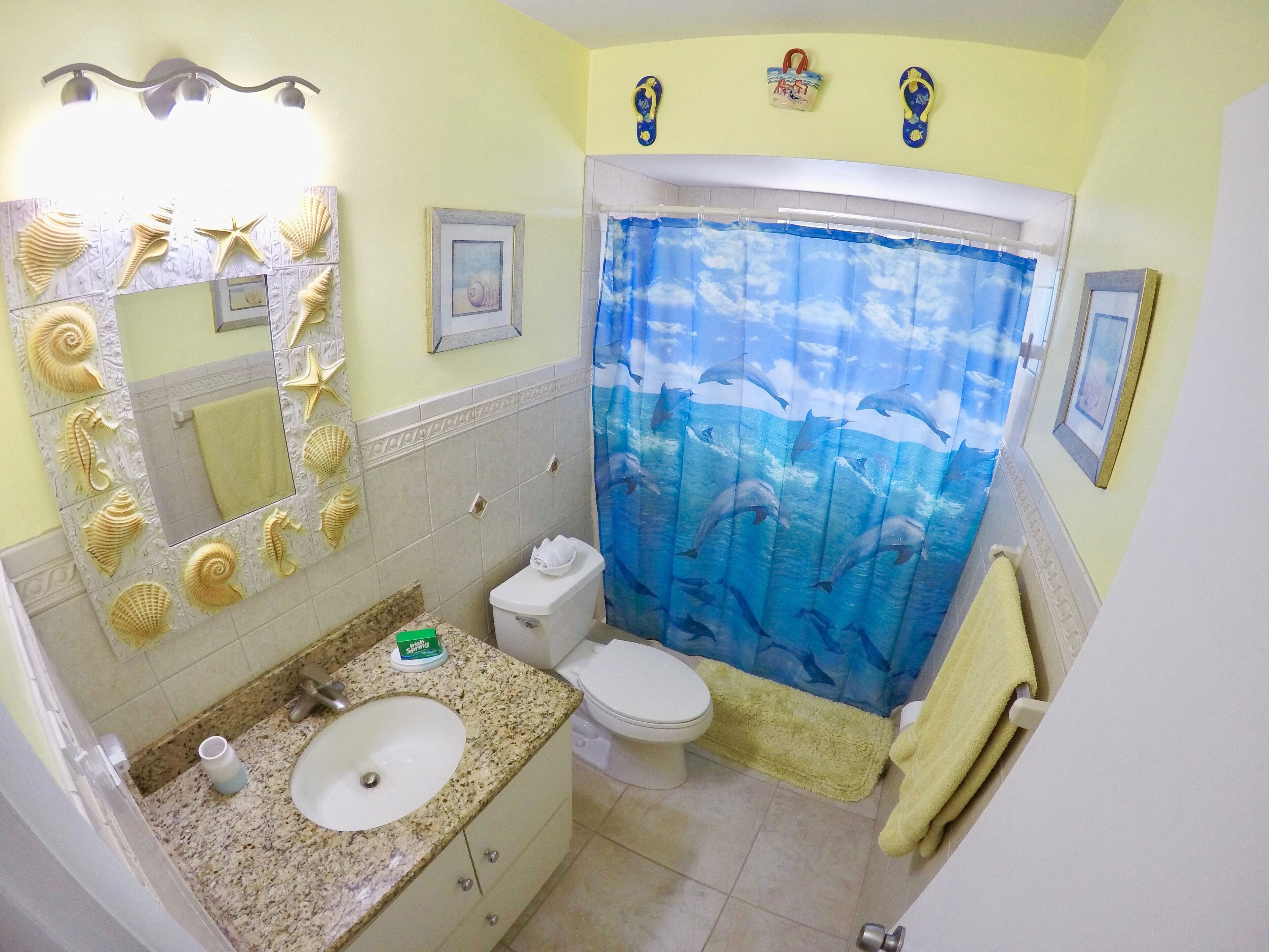 A bathroom with a sink, toilet, and shower curtain with a dolphin design.