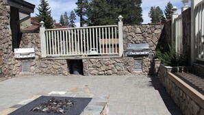 Patio esterno con pareti in pietra, una griglia in metallo e un braciere.