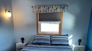 Una camera da letto con un letto, due comodini, una finestra con persiane e un lampadario a parete.