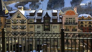 A row of traditional European-style buildings with snow-covered roofs, likely part of a ski resort.