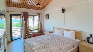 Ein Schlafzimmer mit einem großen Bett, Holzboden und Blick ins Freie durch eine Schiebetür.