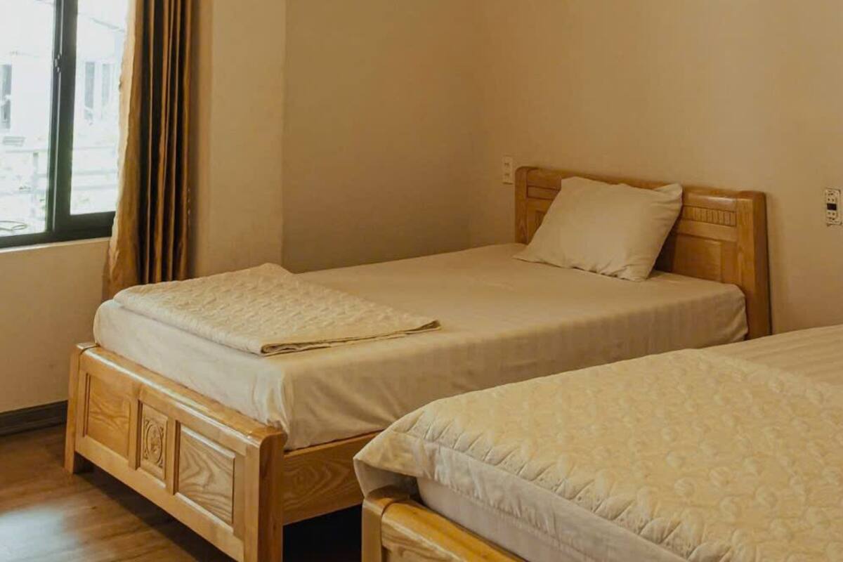 A room with two wooden beds, each with a headboard and a pillow.