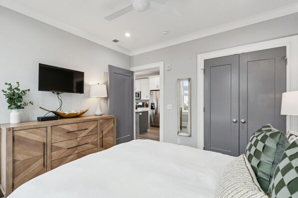 A bedroom with a bed, a TV, a lamp, a dresser, and a mirror.