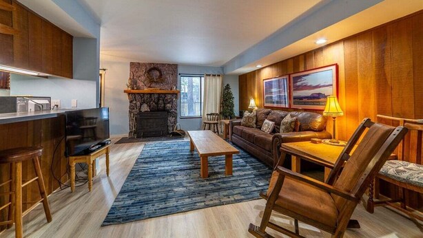 Un salon moderne avec une cheminée, des meubles en bois et un téléviseur.