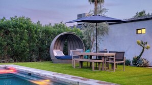 A modern outdoor pool area with a seating arrangement and a pergola. - Stylish Retreat: Heated Pool w/ Jets, Putting Green & Outdoor Kitchen (Phoenix)