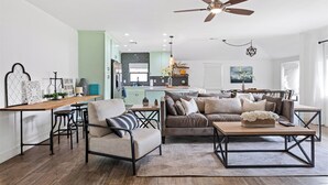 A modern living room with a sofa, armchairs, a coffee table, and a dining area with a wooden table and chairs. - Stylish Retreat: Heated Pool w/ Jets, Putting Green & Outdoor Kitchen (Phoenix)