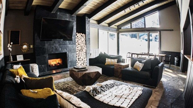 A cozy living room with a stone fireplace, comfortable seating, and a large TV. - Chamonix 40: Near Canyon Lodge (Mammoth Lakes)