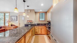 Una cocina moderna con encimeras de granito, armarios de madera y un refrigerador de acero inoxidable.
