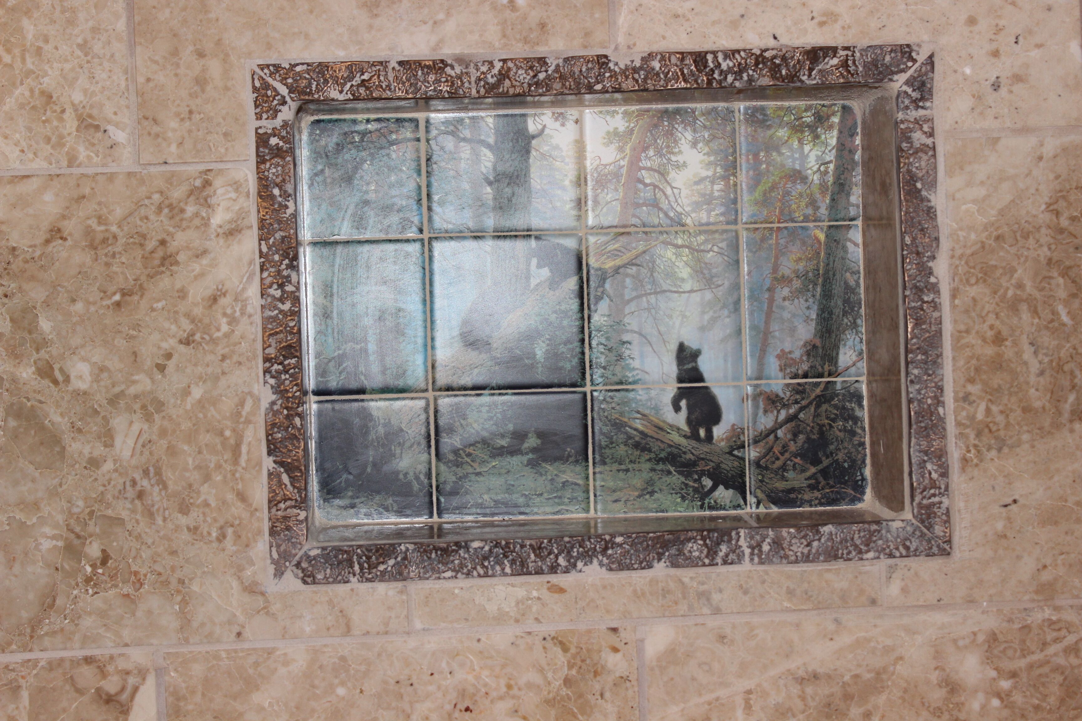A bathroom with a tiled wall and a window with a view of trees.