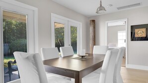 A dining area with a wooden table, white chairs, and a candle centerpiece. - ON HYPOLUXO ISLAND, Incredible Property  - Walk to Beach (Lantana)