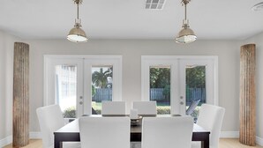 A dining area with a table and chairs, two pendant lights, and a view through the windows. - ON HYPOLUXO ISLAND, Incredible Property  - Walk to Beach (Lantana)