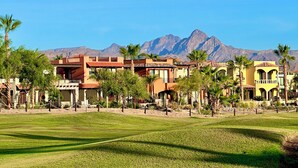 A resort with multiple buildings, a grassy area, and mountains in the background. - Beautiful 2 Bed, 2 Bath Casa Steps From The Beach & Pools In Loreto Bay (Loreto)